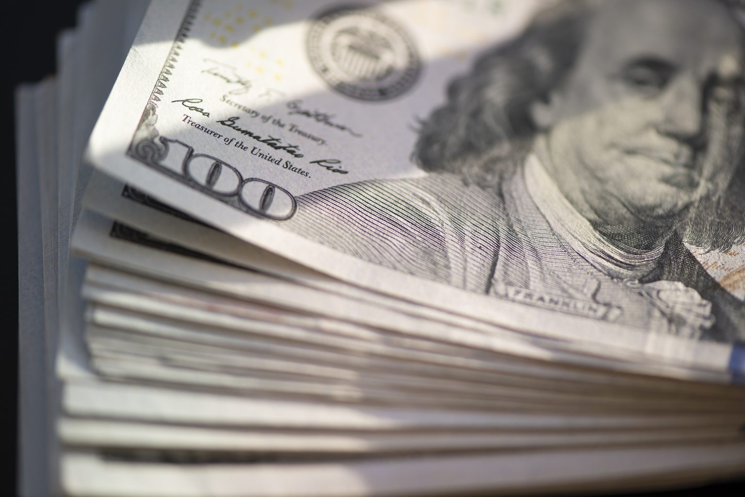 Hundred of US dollars on black background
