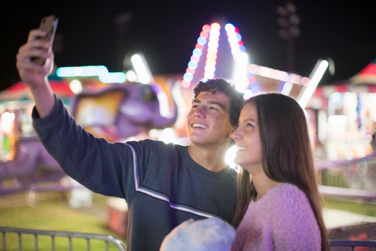 Young teenage couple taking a selfie at a fair