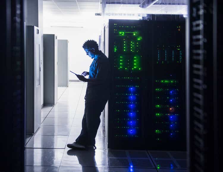 Mid adult man using digital tablet in server room