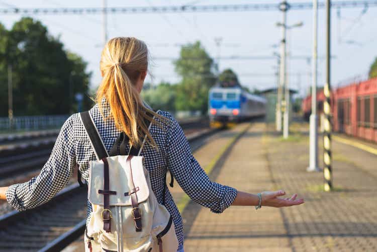Mujer de pie en la estación de ferrocarril y tratando de dejar el tren. Viajero está preocupado, porque extrañaba un tren