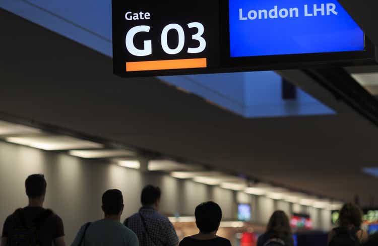 Airport interior with passenger silhouettes, gate number three board and destination "London Heathrow Airport" (LHR)