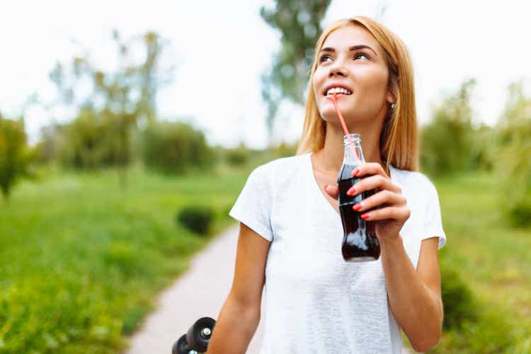 Girl with a skate in the Park, drinking a drink with a glass bottle