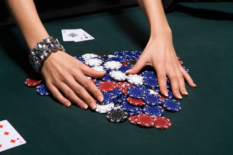 Woman gathering poker chips in casino