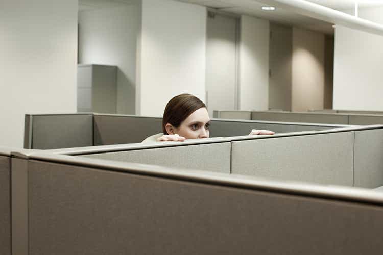 Woman hiding behind cubicle in office