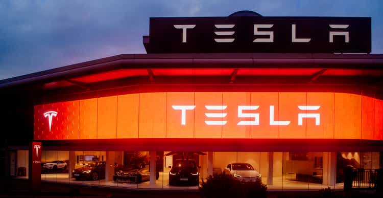 Tesla motors showroom with cars and illuminated logo branding at dusk London UK