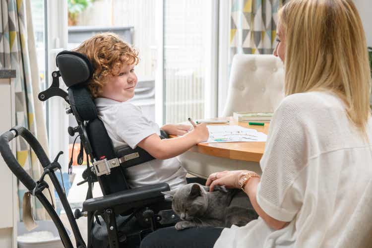 Mother and son in wheelchair with disability at home