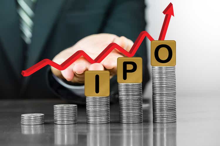 Businessman hand holding red arrow up with the letters IPO on money coin stack arranged as a graph