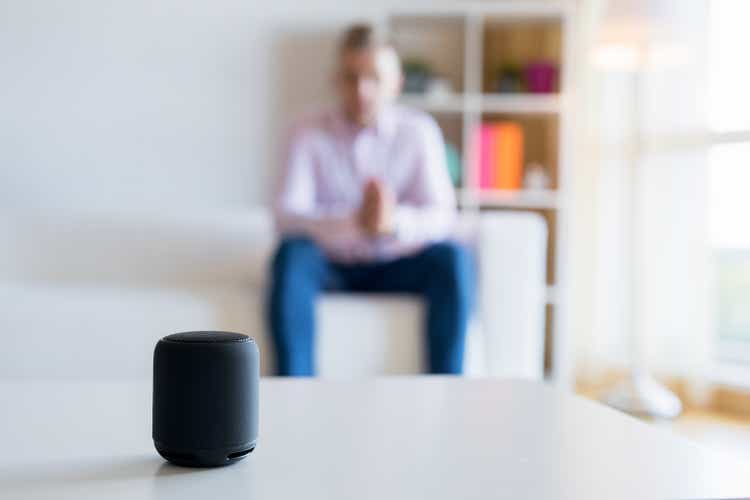 Man talking to virtual assistant smart speaker in living room