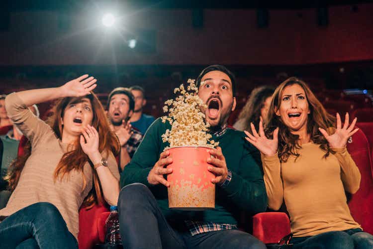 Scared friends spilling popcorn at cinema