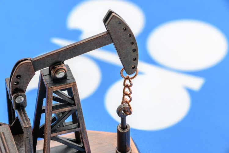 Petroleum, petrodollar and crude oil concept : Oil pump jack and flag of OPEC or Organization of Oil Exporting Countries, depicts the investment in the development or production of global oil industry