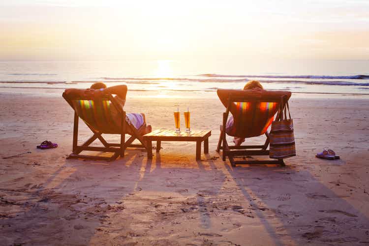 Vacation travel, silhouettes of happy couple relaxing on beach.