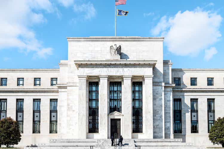 Federal Reserve bank entrance, facade architecture building, wall security guards standing by doors, path, American flags, blue sky