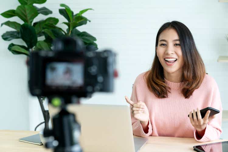 Young attractive asian woman blogger or vlogger looking at camera and talking on video shooting with technology. Social media influencer people or content maker concept in relax casual style at home.
