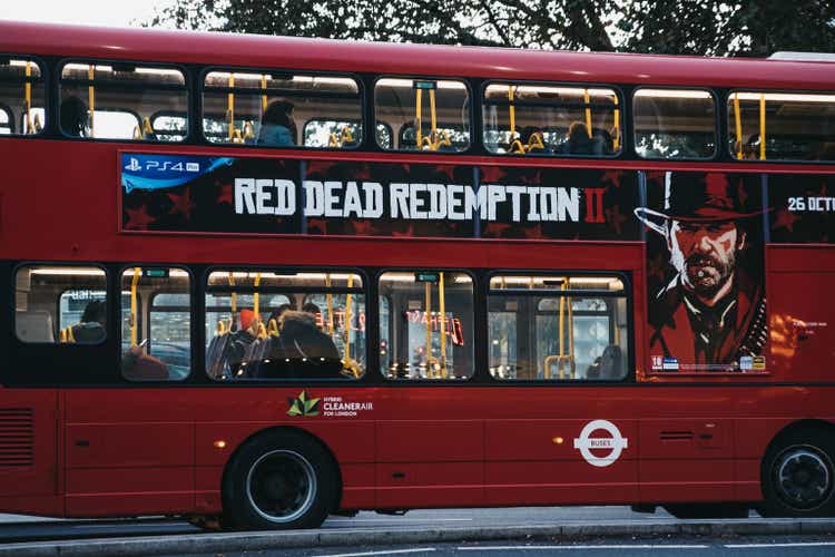Red Dead Redemption 2 game advertisement on a red double decker bus in London, UK.