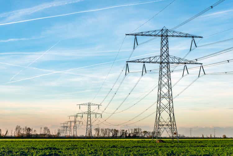 High voltage towers with thick hanging power cables in a rural landscape in the Netherlands