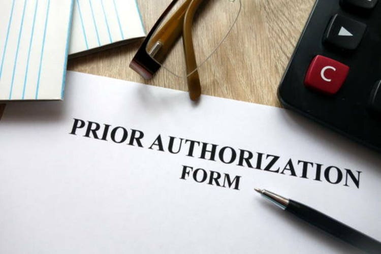 Prior authorization form with pen, calculator and glasses
