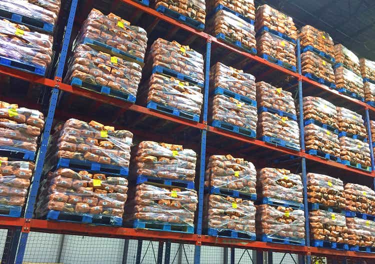 Pallets of potato sacks stacked in distribution center.