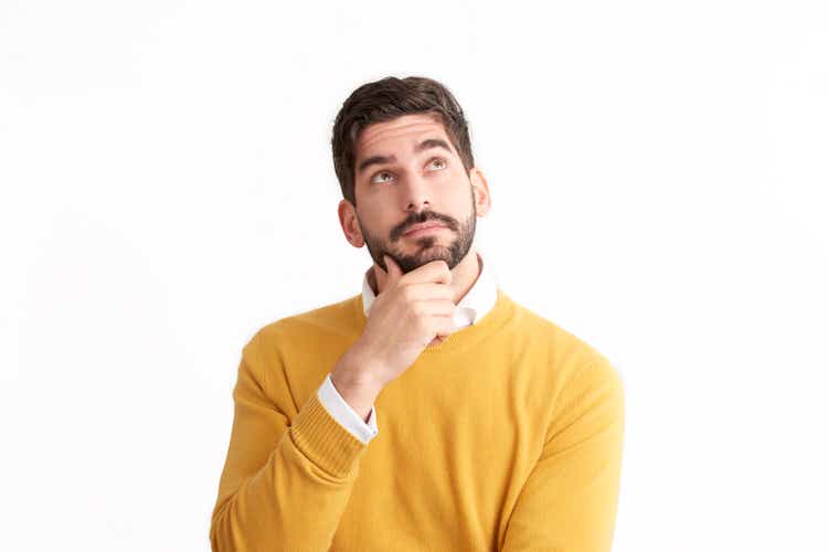 Handsome young man looking thoughtfully at isolated white background with copy space