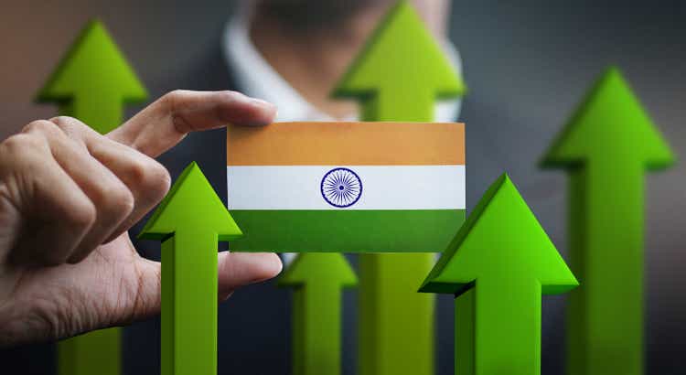 Nation growth concept, green arrows up - businessman holding India flag card