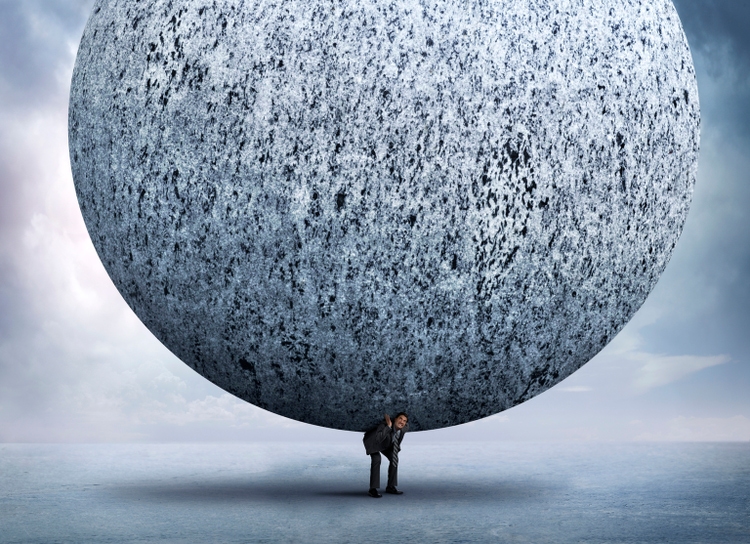 Businessman Bending Over To Support Very Large Stone Sphere On His Back