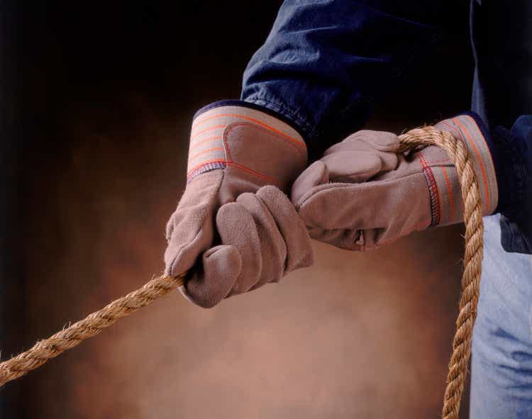 A pair of gloved hands pulling a rope