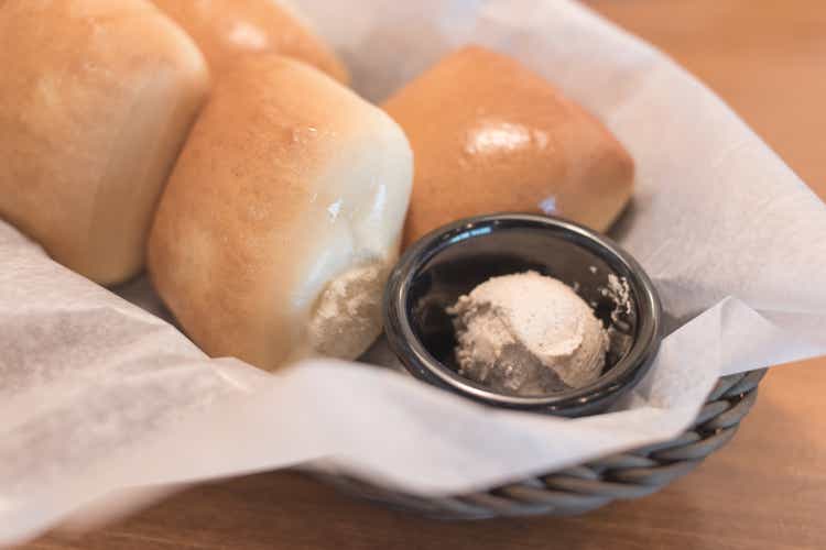 Texas Roadhouse Rolls with Cinnamon Honey Butter in a basket.;