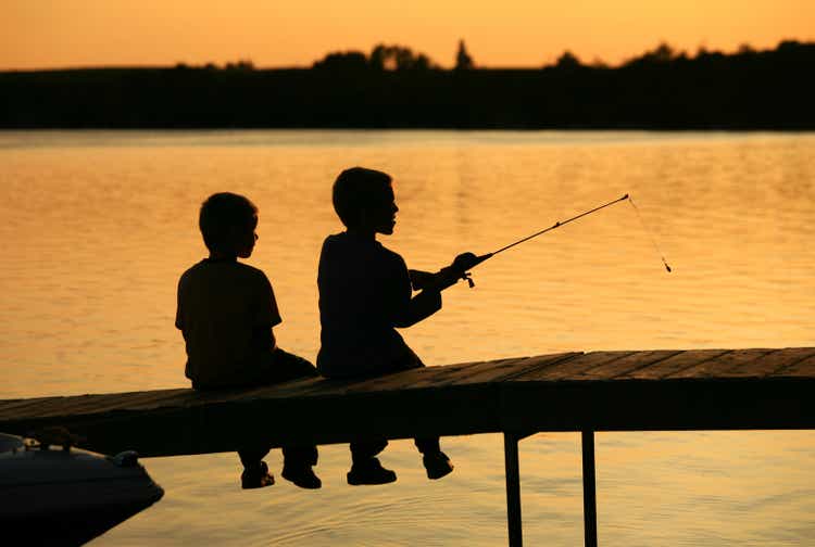 Silhouette of Two Boys Fishing Off A Dock