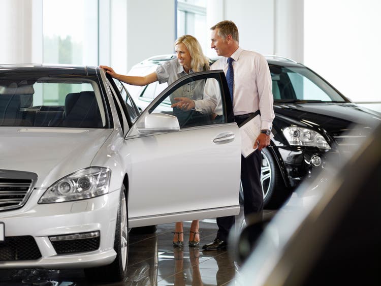 Salesman talking to woman in automobile showroom