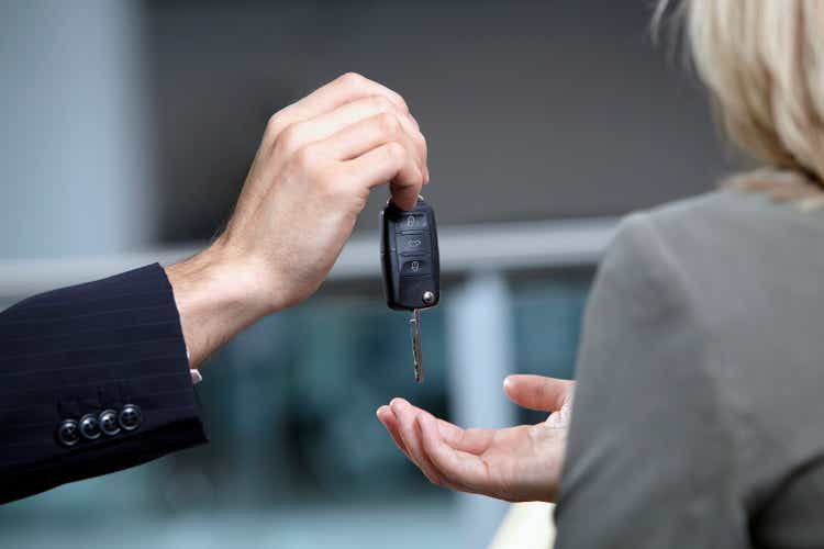 Salesman handing woman car keys in automobile showroom