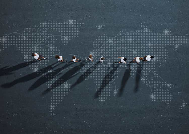 School children in uniforms walking in row across world map