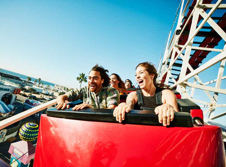 Laughing and screaming couple riding roller coaster at amusement park