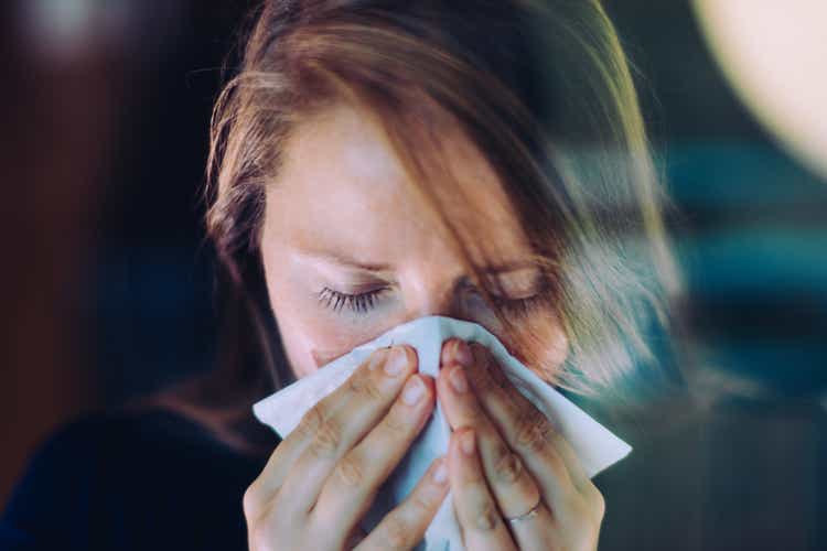 Woman sneezing behind a window.