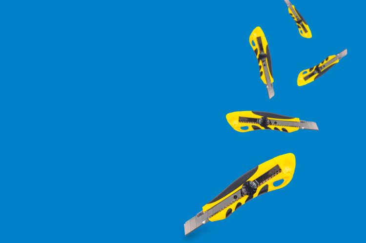 Falling stationery knives with yellow and black plastic handle on blue background with copy space for your text