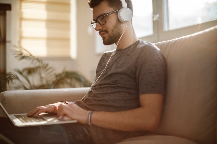 Young man using laptop and listening to music at home