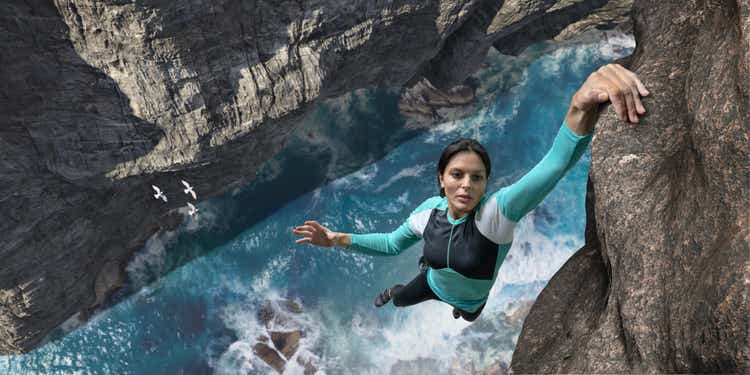 Free Climber Hangs One Handed On Sea Cliff Rock Face