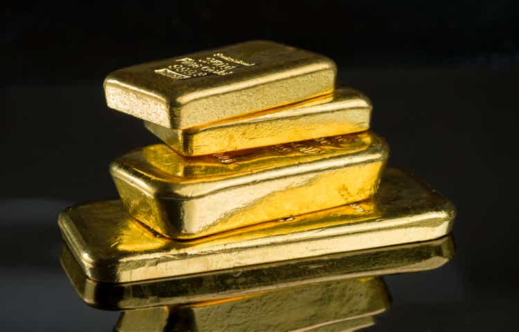 Several gold bars of different weight on a dark mirror surface