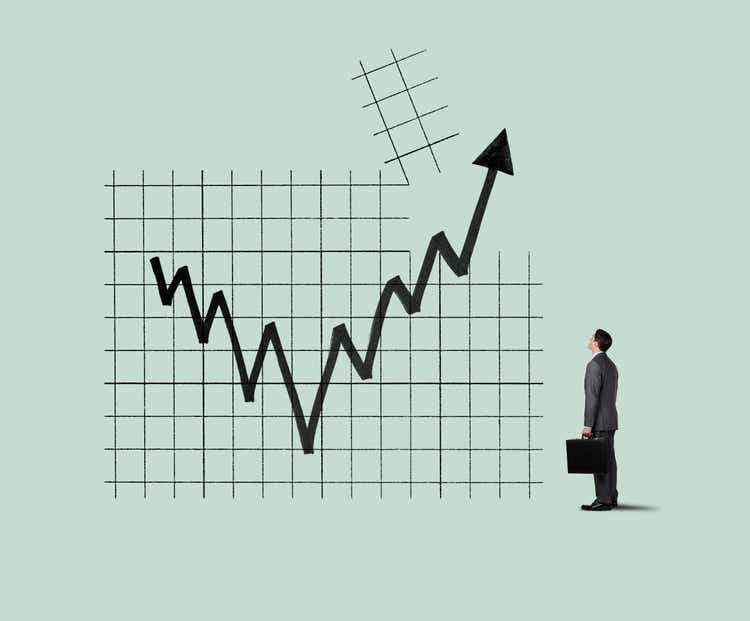 Businessman Looking Up At Chart As Arrow Breaks Through A Chart