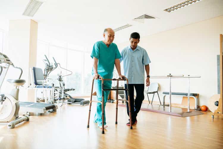 Senior man using walking frame in physiotherapy gym