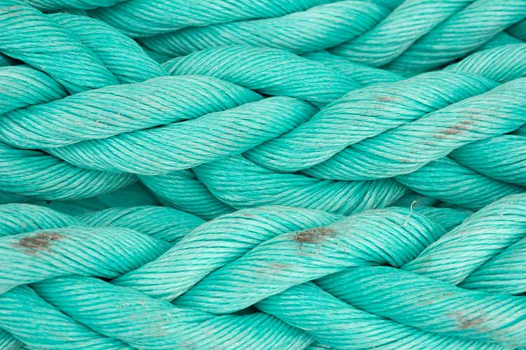 Nautical background. Old blue frayed ship rope closeup.