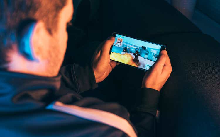 Ocio gamer juega acciĂłn vĂdeo en telĂ©fono mĂłvil por la noche