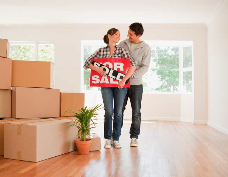 Couple holding sold sign for their new house