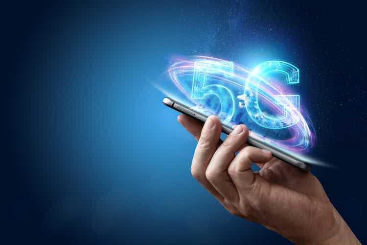 Sfondo creativo, mano maschile che tiene un telefono con un ologramma 5G sullo sfondo della città. Il concetto di rete 5G, Internet mobile ad alta velocità, reti di nuova generazione. Spazio di copia, Supporti misti.