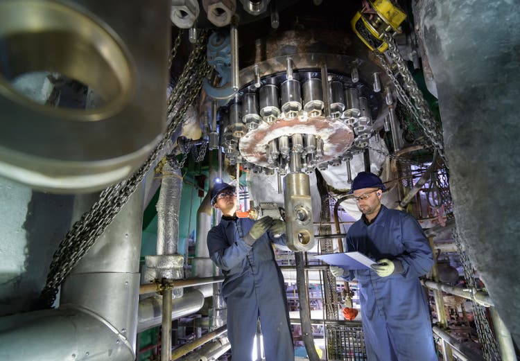 Engineers working in confined space under turbine during outage in nuclear power station