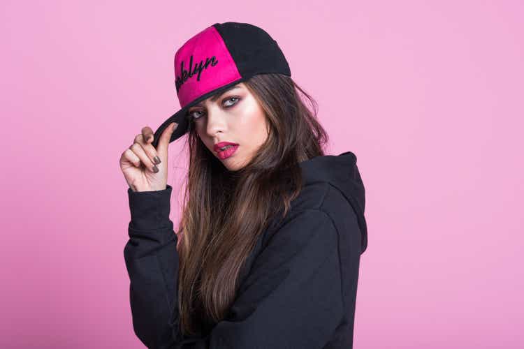 Young woman in black hooded shirt against pink background
