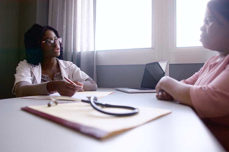 Young Female Doctor discussing a medical report with a senior female patient with medical record