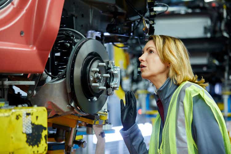 Blond female engineer checking vehicle at factory