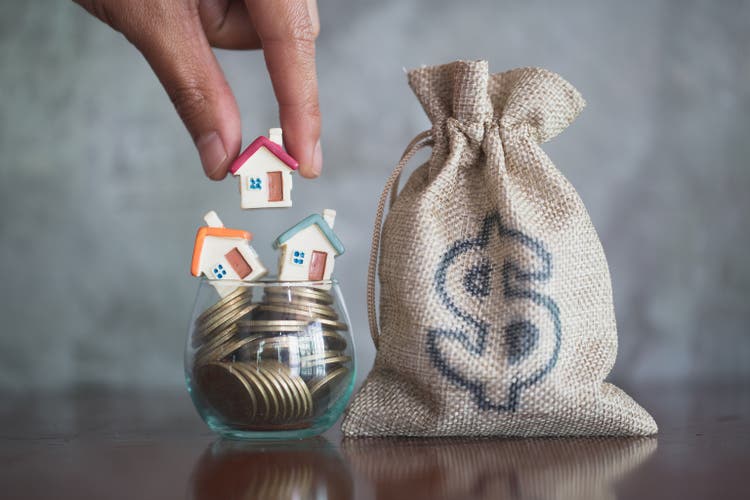 Human hand putting house model on coins stack, planning savings money of coins to buy a home concept, mortgage and real estate investment. saving or investment for a house.