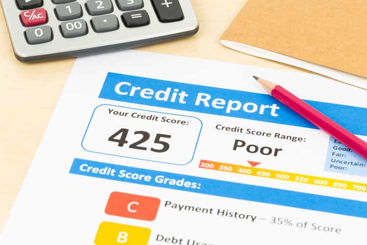 Poor credit score report with pen and calculator; document and the report are mocked-up