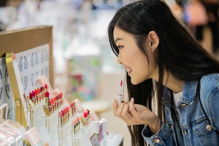 Portrait of Asian woman trying on lipstick