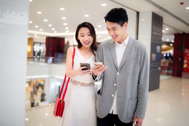 Young couple walking and using smartphones in a shopping mall